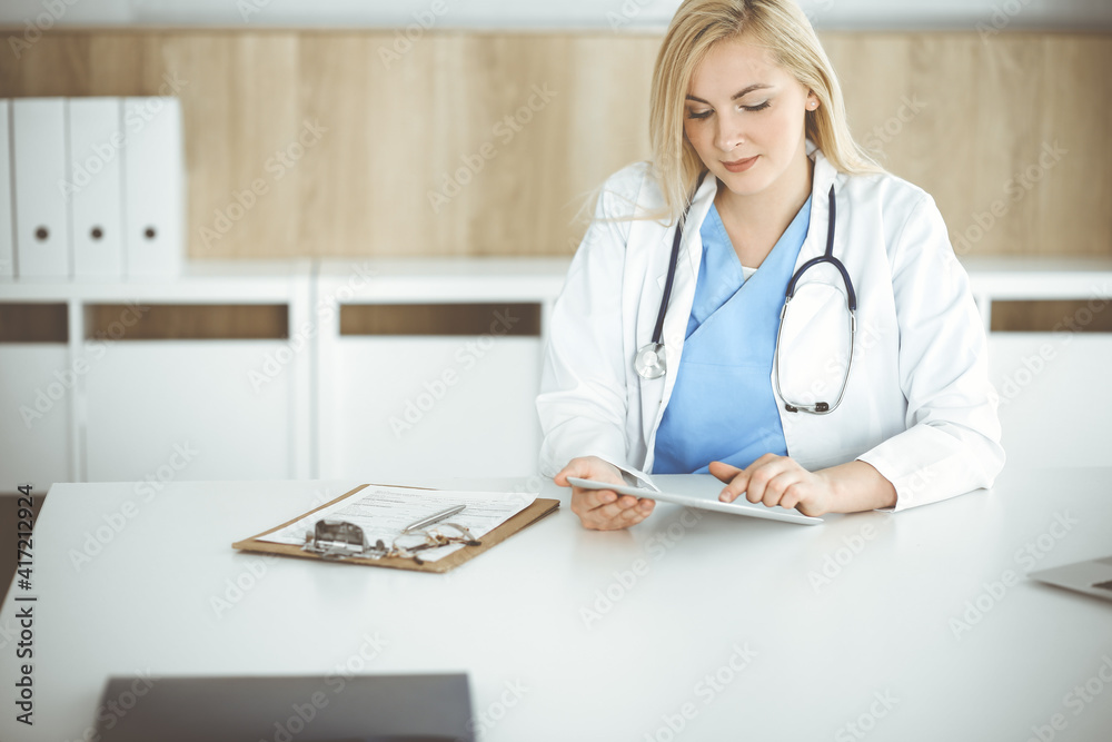 Woman-doctor standing in hospital or clinic and using tablet pc. Data and best service in medicine and healthcare Woman-doctor standing in hospital or clinic and using tablet pc. Data and best service in medicine and healthcare
