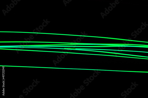 Green thin lines of light on black background. Laser irregular light beams. Luminous, bright threads of green color with high density.