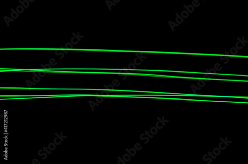 Green thin lines of light on black background. Laser irregular light beams. Luminous, bright threads of green color with high density.