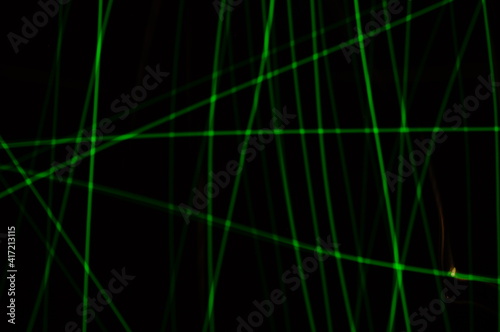 Green thin lines of light on black background. Laser irregular light beams. Luminous, bright threads of green color with high density.