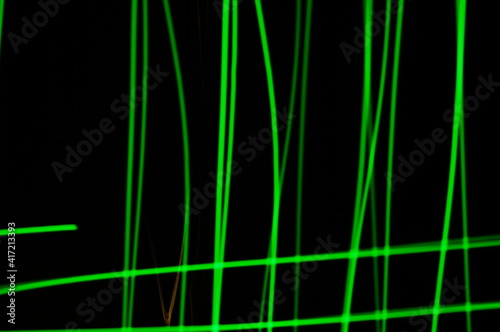Green thin lines of light on black background. Laser irregular light beams. Luminous, bright threads of green color with high density.