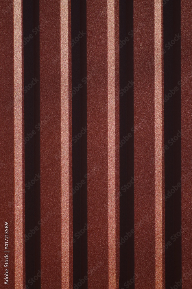 Background with symmetrical brown straight lines. Trapezoidal sheet metal wall. Metal sheet metal design in embossed pattern. Simple decorative stencil on corrugated metal sheet. Background with symmetrical brown straight lines. Trapezoidal sheet metal wall. Metal sheet metal design in embossed pattern. Simple decorative stencil on corrugated metal sheet.