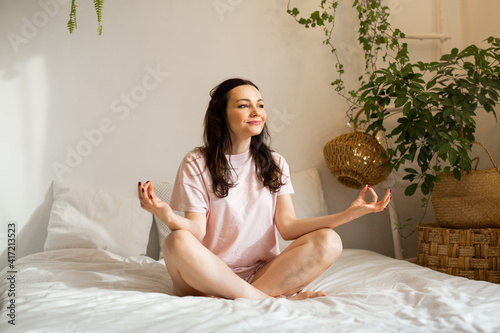 beautiful young woman on bed in yoga pose 