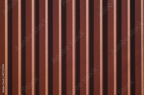 Background with symmetrical brown straight lines. Trapezoidal sheet metal wall. Metal sheet metal design in embossed pattern. Simple decorative stencil on corrugated metal sheet.