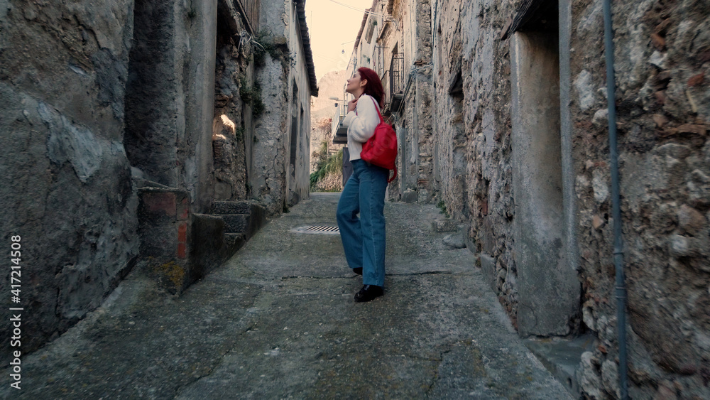 Giovane ragazza con jeans cammina per la città abbandonata Giovane ragazza con jeans cammina per la città abbandonata