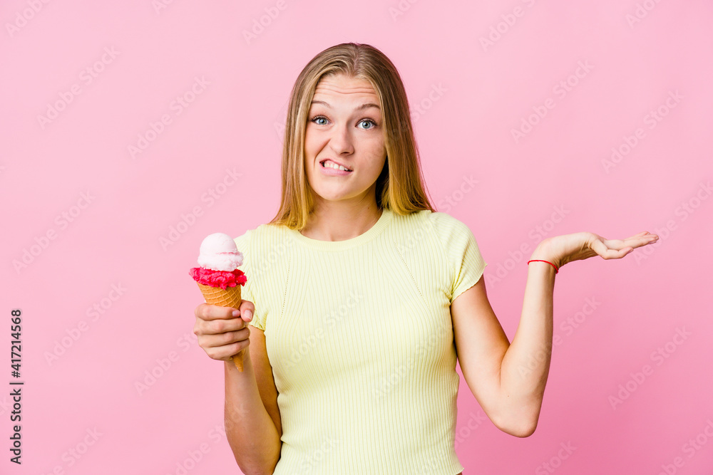 Young russian woman eating an ice cream isolated confused and doubtful shrugging shoulders to hold a copy space. Young russian woman eating an ice cream isolated confused and doubtful shrugging shoulders to hold a copy space.