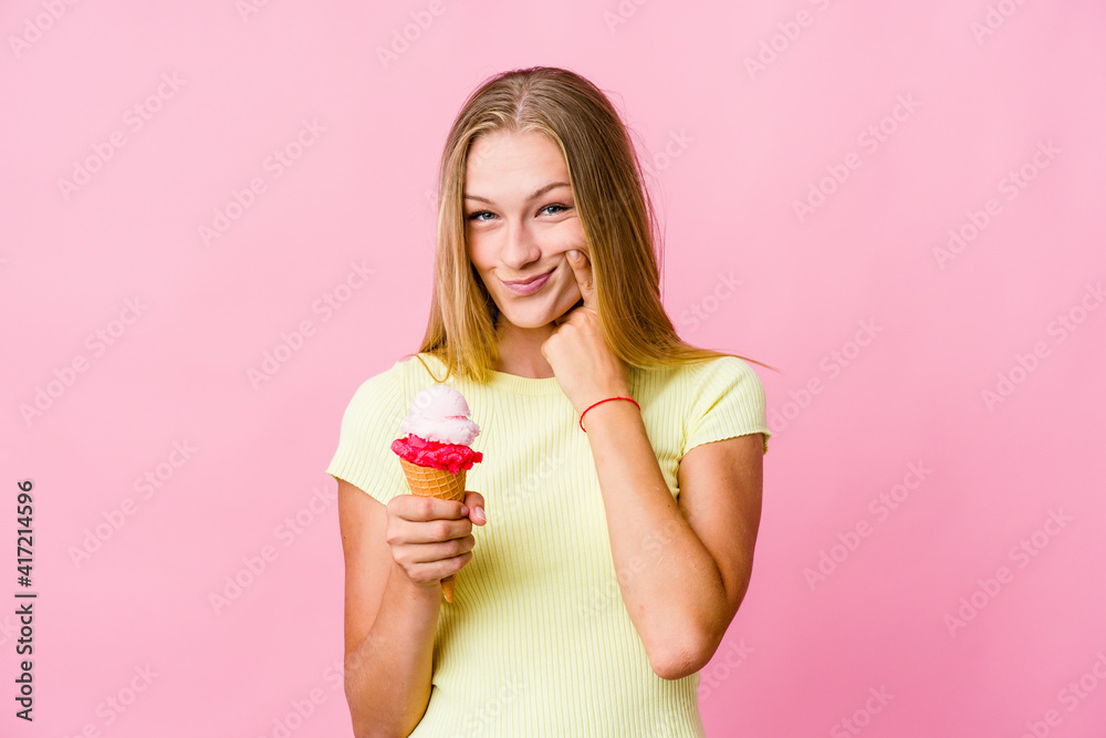 Young russian woman eating an ice cream isolated doubting between two options.