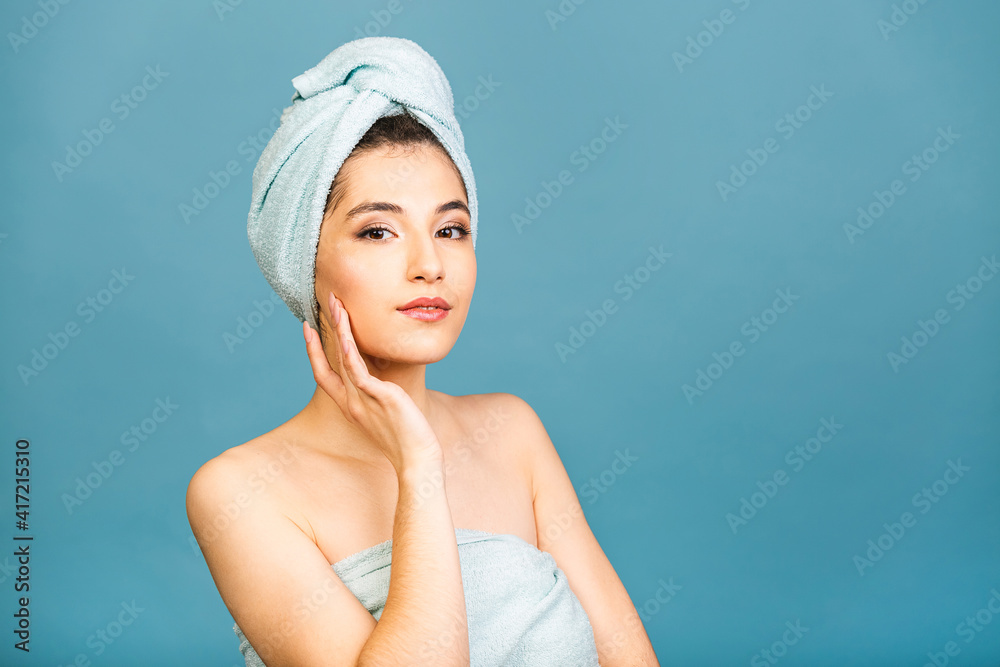 Beautiful happy young spa girl isolated on blue background. Woman in a blue towel on a head. Happy woman after bath with clean perfect skin. Beautiful happy young spa girl isolated on blue background. Woman in a blue towel on a head. Happy woman after bath with clean perfect skin.