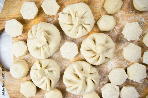Handmade khinkali dumplings and ravioli are beautifully arranged in rows on a cutting board and sprinkled with flour. Close-up, macro.