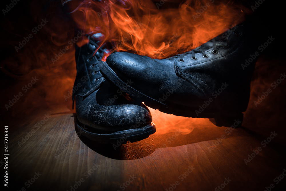 War concept. Old military shoe in a dark toned foggy background. Creative concept of conflict between countries, military aggression. War concept. Old military shoe in a dark toned foggy background. Creative concept of conflict between countries, military aggression.