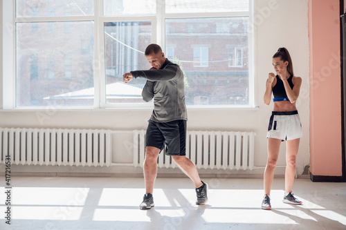 The first training of a novice girl fighter in kickboxing, the coach shows the blows