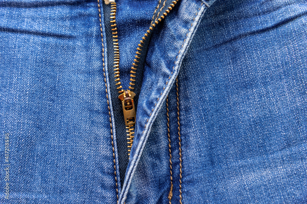 Close up of a zipper half unzipped on a of blue jeans with space for text Close up of a zipper half unzipped on a of blue jeans with space for text