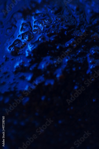 Abstract blue mysterious background. Rough texture in dark light. Oily, oily ooze with bubbles and lumps. Dark uneven background with reflected blue light. 3d illustration with gestural texture.