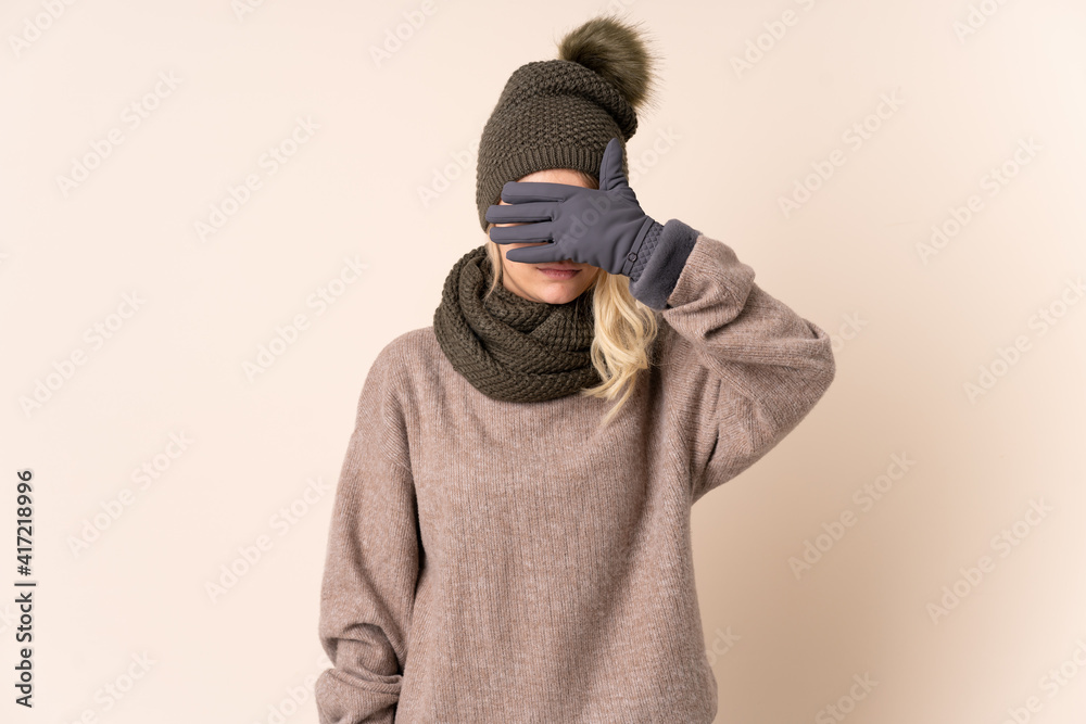Young woman with winter hat over isolated background covering eyes by hands Young woman with winter hat over isolated background covering eyes by hands