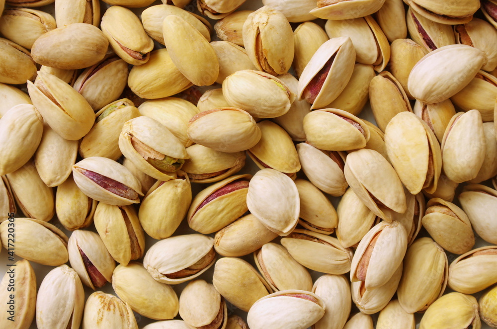 Tasty pistachios as background texture, flat lay. Pile of pistachios in the peel close up. Pistachios healthy omega-3 fatty acid. Healthy food and snacks vegan food. 