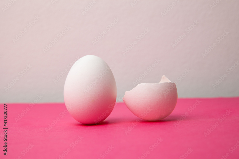 White eggs near broken shell on pink table