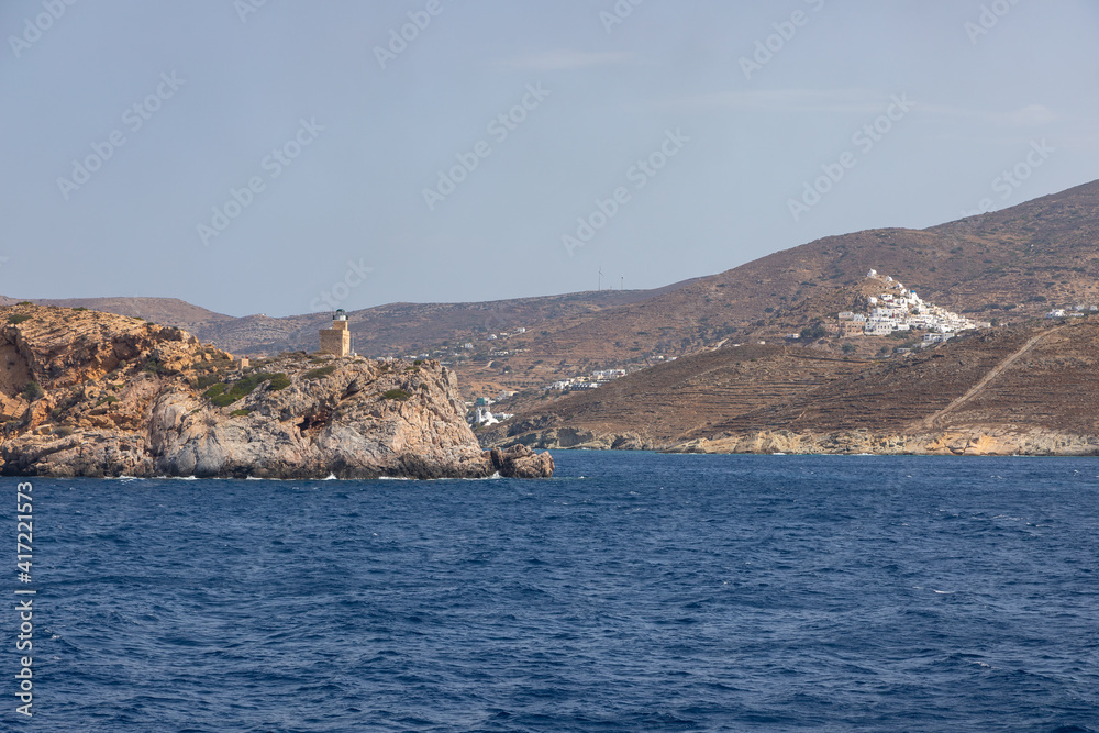 Lighthouse on the rock in the background. Chora , Ios Island, Greece. Lighthouse on the rock in the background. Chora , Ios Island, Greece.