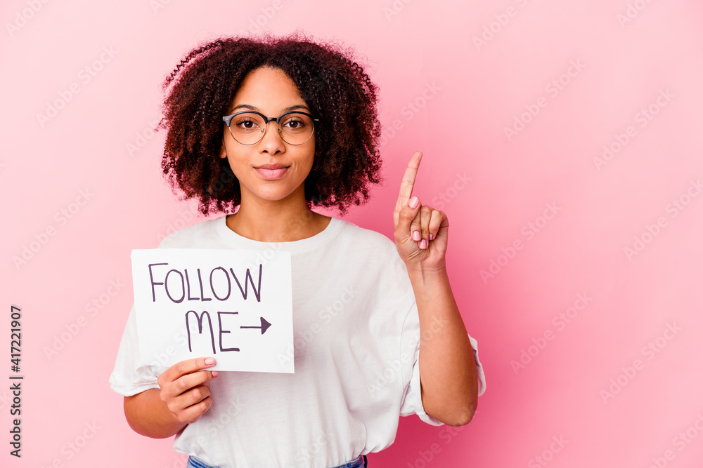 Young african american mixed race woman holding a follow me concept showing number one with finger. Young african american mixed race woman holding a follow me concept showing number one with finger.
