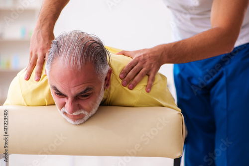 Old male patient visiting young male doctor chiropractor