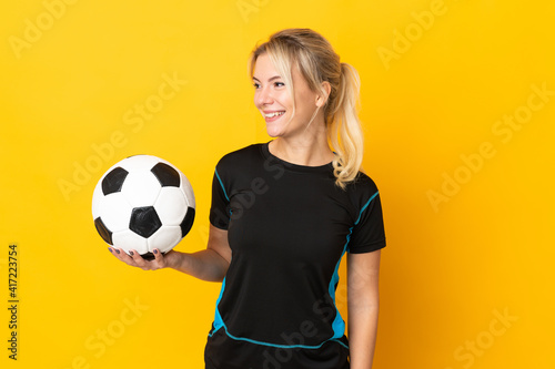 Young Russian football player woman isolated on yellow background looking side