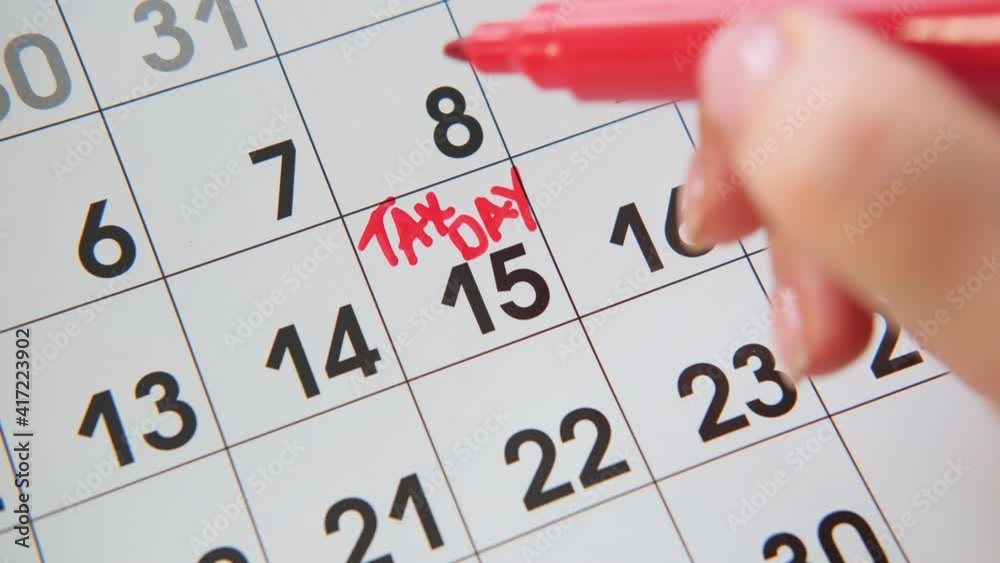 Closeup Womans hand of writing TAX DAY on calendar, April15 or July each year. Closeup Womans hand of writing TAX DAY on calendar, April15 or July each year.
