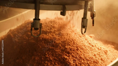 Close up scene of lid steaming tank pouring beans out after high-pressure steam from a big iron bucket, working in a factory. Heavy industry with large boilers steam systems.