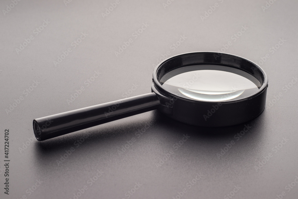 Magnifying glass with plastic handle on a dark background, selective focus Magnifying glass with plastic handle on a dark background, selective focus
