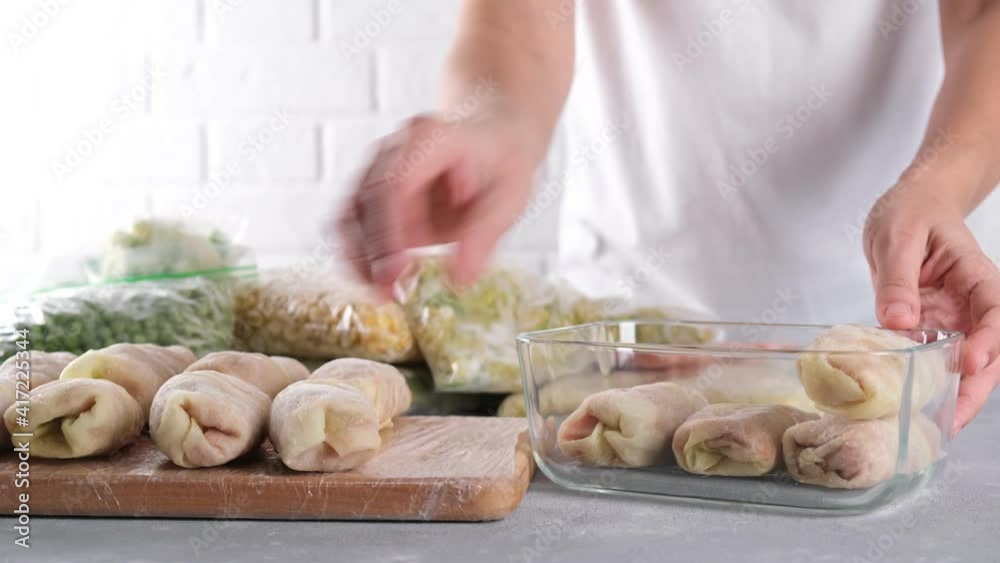 Frozen food. Woman packing frozen stuffed cabbage roll in a glass container. Semi-finished products on the table Frozen food. Woman packing frozen stuffed cabbage roll in a glass container. Semi-finished products on the table