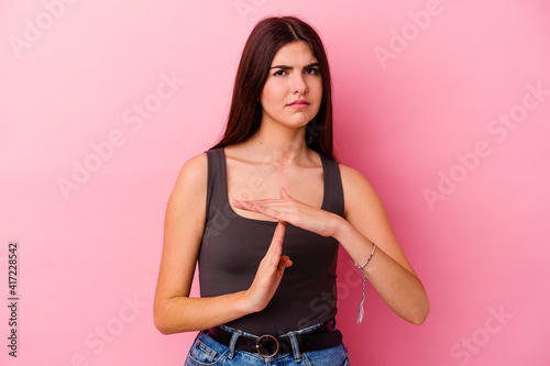Young caucasian woman isolated on pink background showing a timeout gesture. © Asier