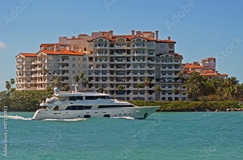 Luxury motor yacht cruising by luxury island condominiums in Miami,Forida. photo