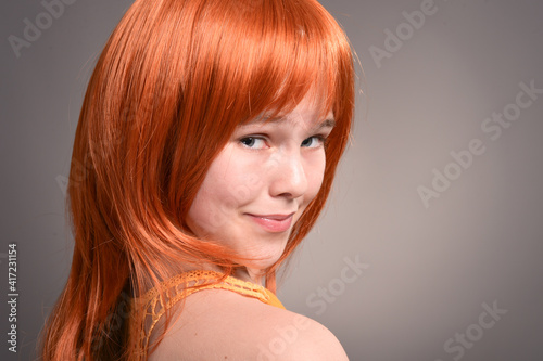 Portrait of cute girl with red hair posing in studio