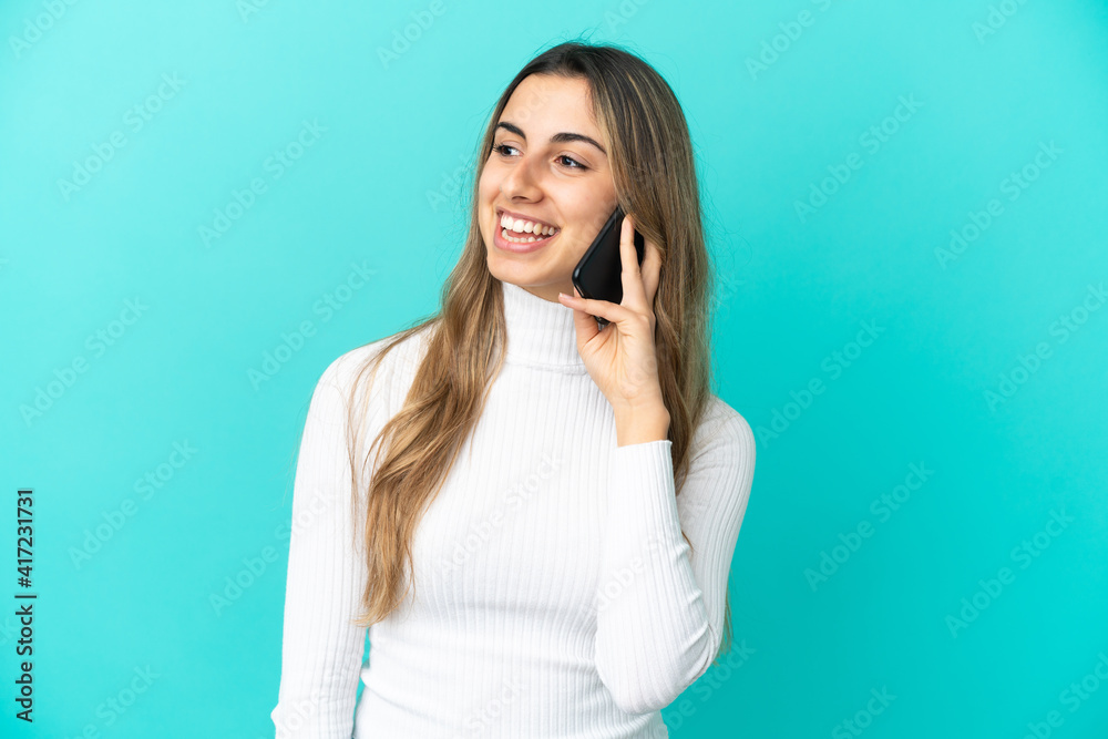 Young caucasian woman using mobile phone isolated on blue background looking to the side and smiling Young caucasian woman using mobile phone isolated on blue background looking to the side and smiling