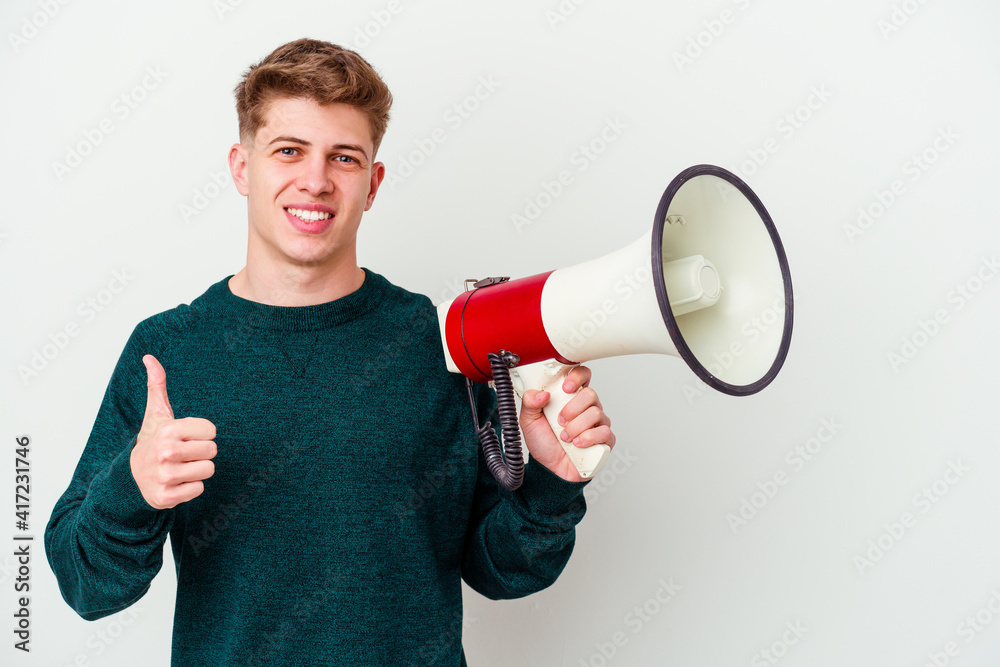 Young caucasian man holding a megaphone isolated on white background smiling and raising thumb up Young caucasian man holding a megaphone isolated on white background smiling and raising thumb up