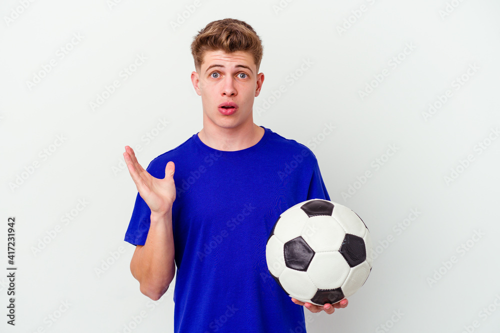 Young caucasian man playing soccer isolated on background surprised and shocked. Young caucasian man playing soccer isolated on background surprised and shocked.