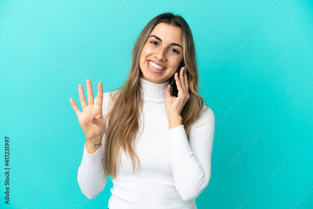Young caucasian woman using mobile phone isolated on blue background happy and counting four with fingers Young caucasian woman using mobile phone isolated on blue background happy and counting four with fingers
