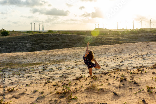 Menina brinca e se diverte com exercícios em dunas de areia ao por do sol photo