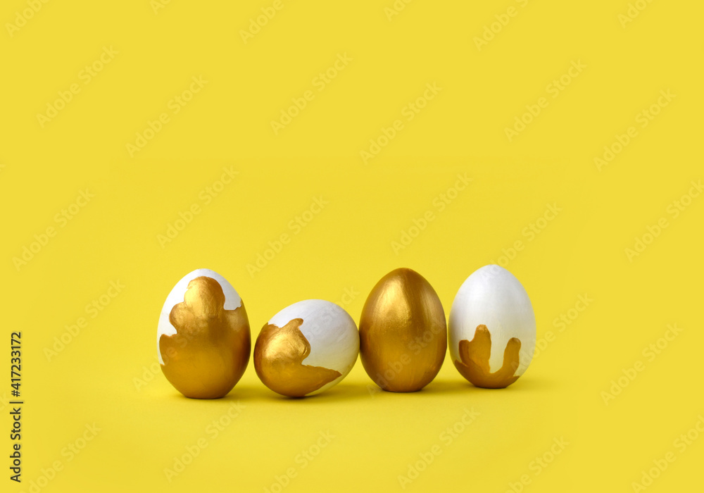 Minimalist Easter composition. Golden decorated eggs in row on yellow background. Trendy color concept. Happy Easter greeting card with copyspace. Minimalist Easter composition. Golden decorated eggs in row on yellow background. Trendy color concept. Happy Easter greeting card with copyspace.