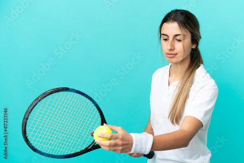 Young caucasian woman isolated on blue background playing tennis © luismolinero
