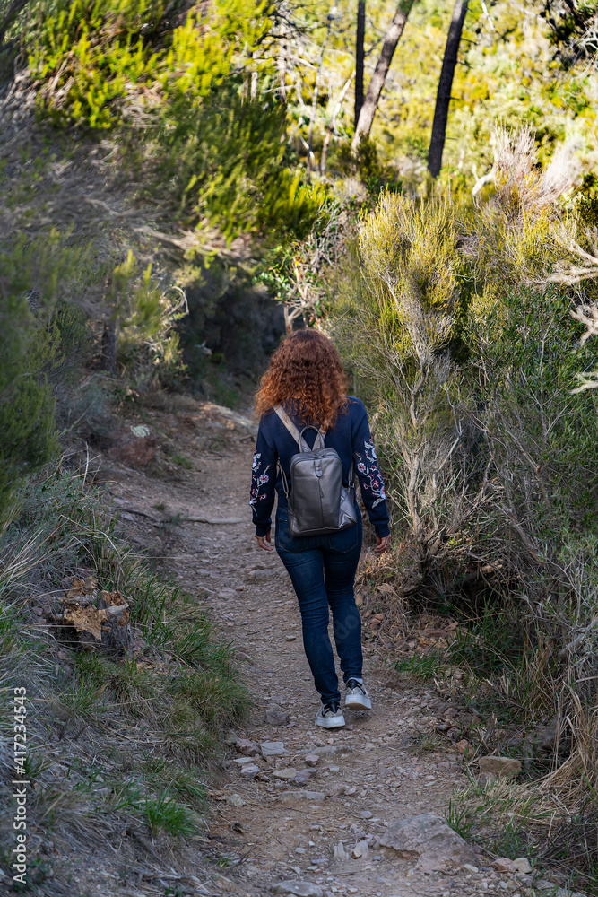 Young woman with a backpack goes hiking in the mountains of Theoule-sur-Mer city on the Mediterranean coast of France. Young woman with a backpack goes hiking in the mountains of Theoule-sur-Mer city on the Mediterranean coast of France.