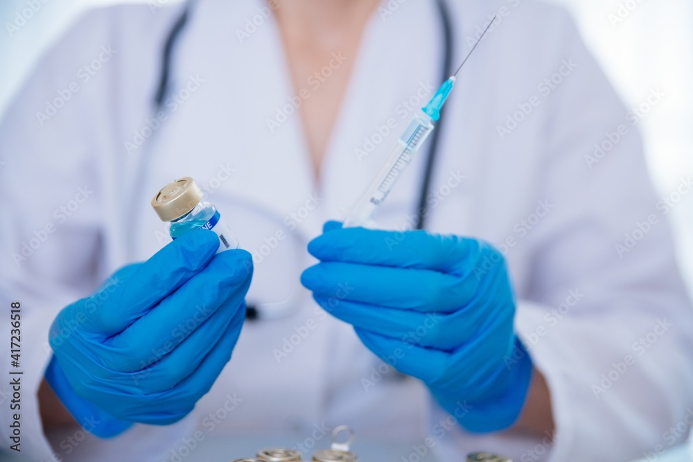 Female doctor in the laboratory with test tube and syringe. Looking for a vaccine for Coronavirus COVID-19. Female doctor in the laboratory with test tube and syringe. Looking for a vaccine for Coronavirus COVID-19.