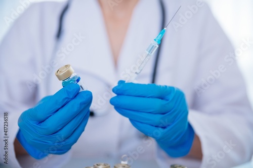 Female doctor in the laboratory with test tube and syringe. Looking for a vaccine for Coronavirus COVID-19.