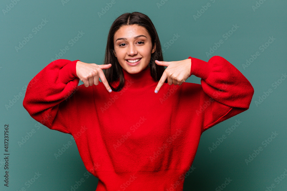Fototapeta premium Young Indian woman isolated on blue background points down with fingers, positive feeling.