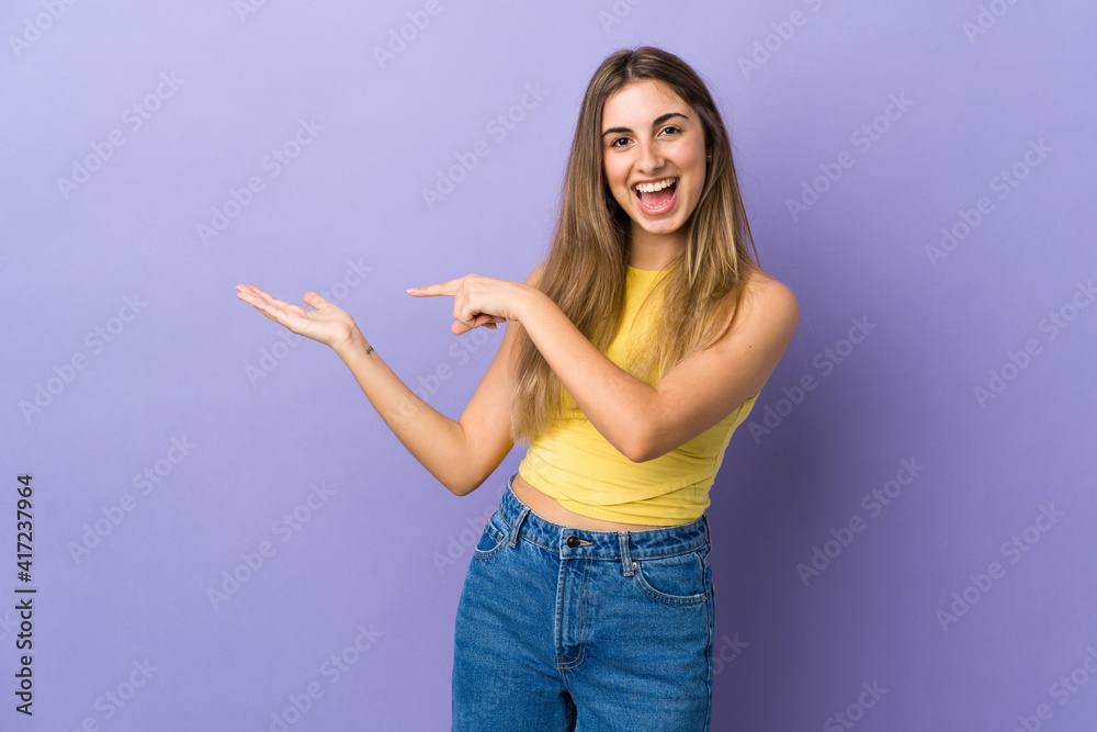 Young woman over isolated purple background holding copyspace imaginary on the palm to insert an ad Young woman over isolated purple background holding copyspace imaginary on the palm to insert an ad