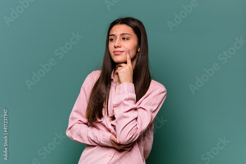 Young Indian woman isolated on blue background contemplating, planning a strategy, thinking about the way of a business.