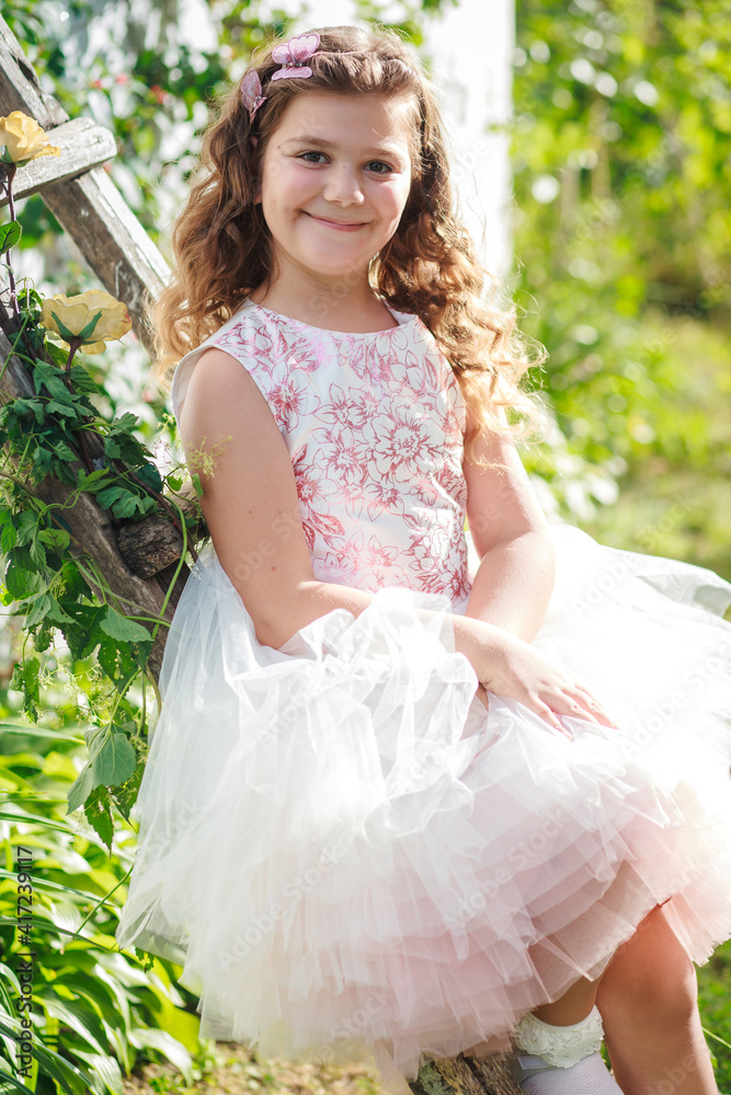 A beautiful girl sits on a wooden staircase decorated with flowers against the backdrop of nature A beautiful girl sits on a wooden staircase decorated with flowers against the backdrop of nature