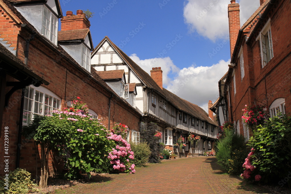 Half Timbered Black & White & brick Houses in Shakespeare's Country Malt Mill Lane Alcester Warwickshire, UK. With floral blooms in High Summer.