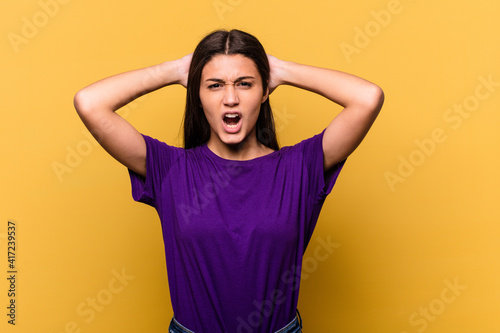 Young Indian woman isolated on yellow background screaming with rage. © Asier
