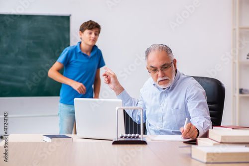 Old male teacher and schoolboy in the classroom