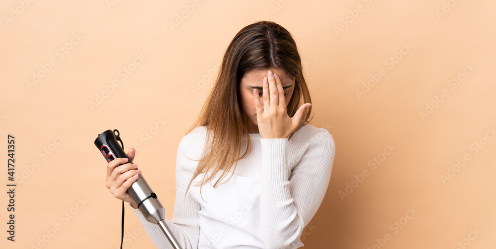 Woman using hand blender over isolated background with tired and sick expression Woman using hand blender over isolated background with tired and sick expression