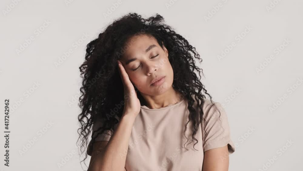 Young African American woman with dark fluffy hair looking tired isolated on white background. After hard day at work